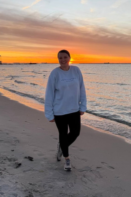 A photo of Emily on the beach while the sun sets. 