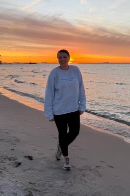 A photo of Emily on the beach while the sun sets.