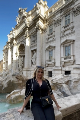 A photo of Larisa sitting near a historic building. 