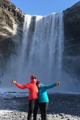 A photo of Emily posing with a waterfall in Iceland.