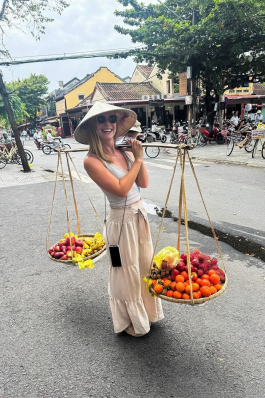 A photo of Lex holding fruit in Vietnam. 