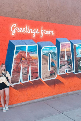 A photo of Lex posing next to a Moab, Utah mural. 