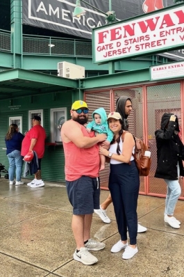 Chelsea, her daughter and husband posing outside of Fenway Park. 