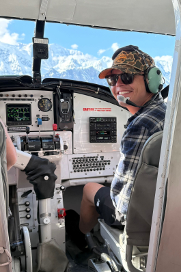 August smiling in the passenger seat of a helicopter. 