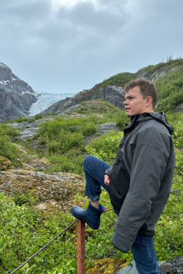 August posing in front of a lush valley. 