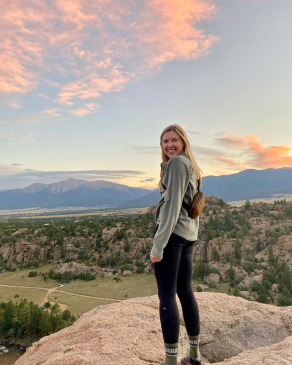 Allison Jones overlooking a rocky cliffside at the hillside and mountains beyond