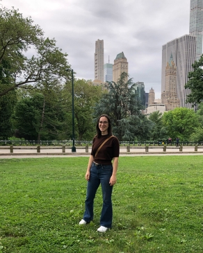 Amanda Pfeil standing in the grass in Central Park with tall buildings in the background