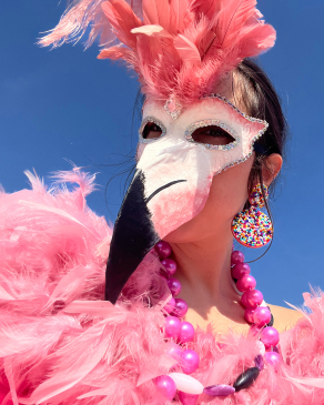 Amanda Pfeil wearing a feathered and sequined pink flamingo mask and costume