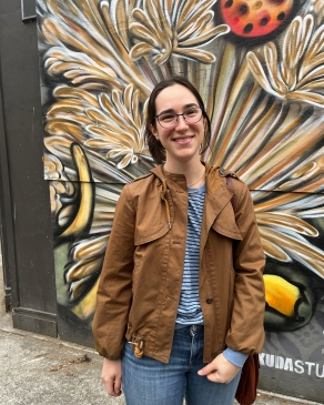 Amanda Pfeil smiling in front of a mural that looks vaguely floral