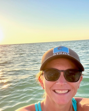 Amanda Steward with ocean and the setting sun behind her