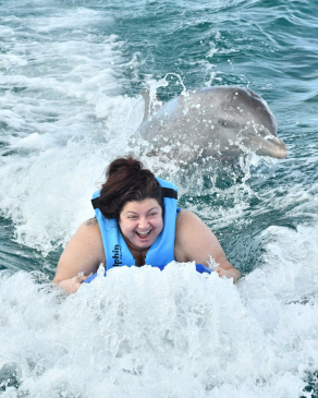 Andraya Ticola being towed through the water accompanied by dolphins