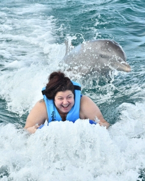Andraya Ticola being towed through the water accompanied by dolphins