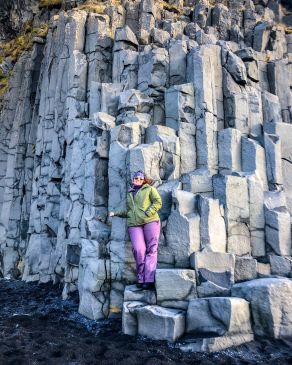 Angela Vaughn leaning against a wall of rectangular-shaped rock pillars