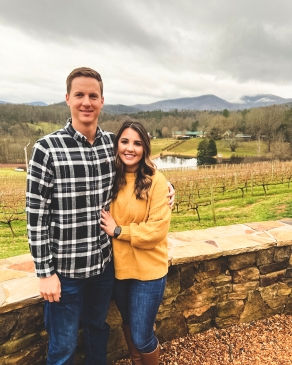 Ashlyn Johnson in front of a rock wall with fields, a lake and the Blue Ridge Mountains in the distance