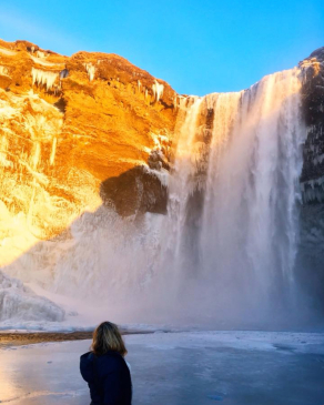 Britt Mattie in front of a large rushing waterfall in Iceland