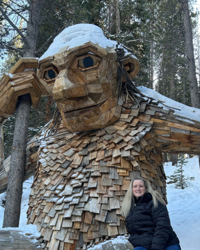 Melissa Bowman in front of a large wooden troll sculpture in Breckenridge, CO