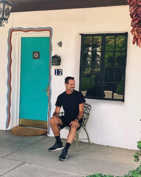 Peter Hosmer in front of a colorful doorway with dried chilis hanging from the porch in Santa Fe