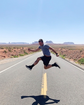 Peter Hosmer jumping in the air on an empty desert road in Utah