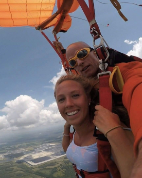 Amy Olschefskie attached to a tandem skydiving rig with her guide strapped behind her