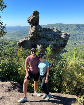 a couple standing on a rock in front of mountains
