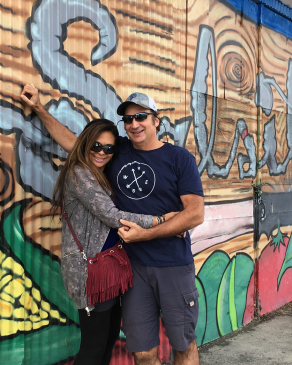 John Deleva and his wife in front of a mural