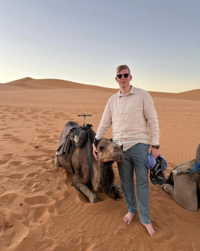 A photo of Dylan next to a camel in the Sahara
