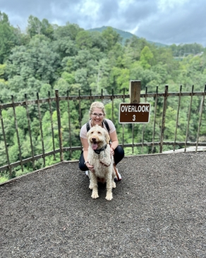 A photo of Anna and her dog at an overlook of a state park.