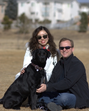 A photo of Wenjie and a dog in a Denver field. 