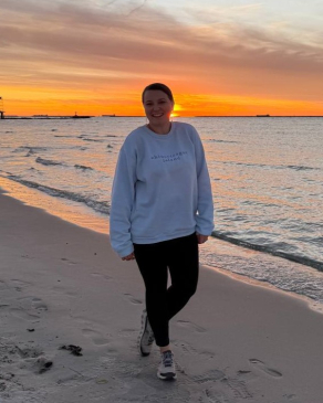 A photo of Emily on the beach while the sun sets. 