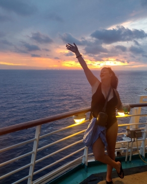 A photo of Kathy standing at a deck on her cruise. 