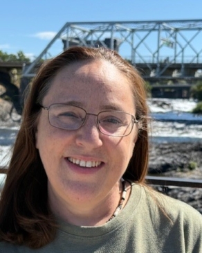 A photo of Lori, with a bridge resting behind her. 