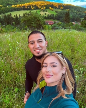 A photo of Larisa and her partner standing in a grassy plain. 