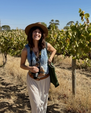 A photo of Kylie near a vineyard. 
