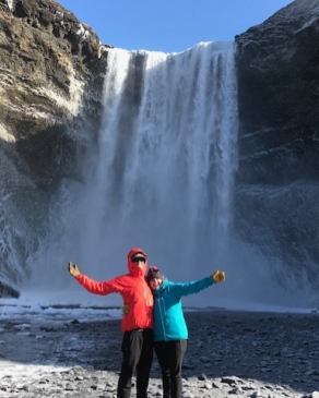 A photo of Emily posing with a waterfall in Iceland. 