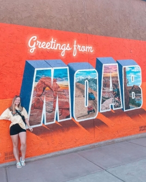 A photo of Lex posing next to a Moab, Utah mural. 