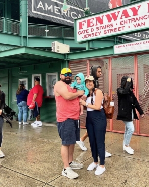 Chelsea, her daughter and husband posing outside of Fenway Park. 