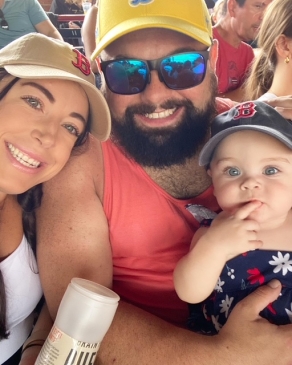 Chelsea, her husband and her daughter smiling at the camera. 