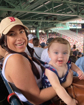 Chelsea and her daughter smiling at a baseball game. 