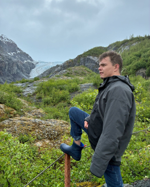 August posing in front of a lush valley. 