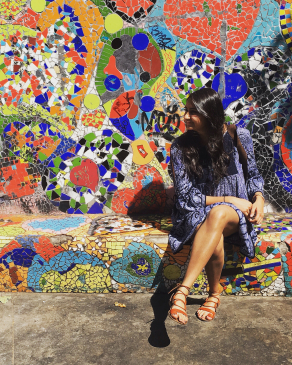Amee sits in front of a mural in Chile. 
